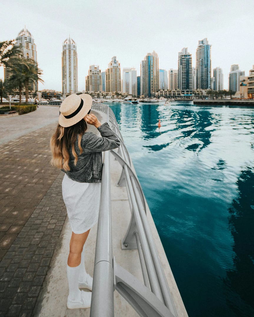 Woman enjoying the view of Dubai Marina under a clear summer sky.